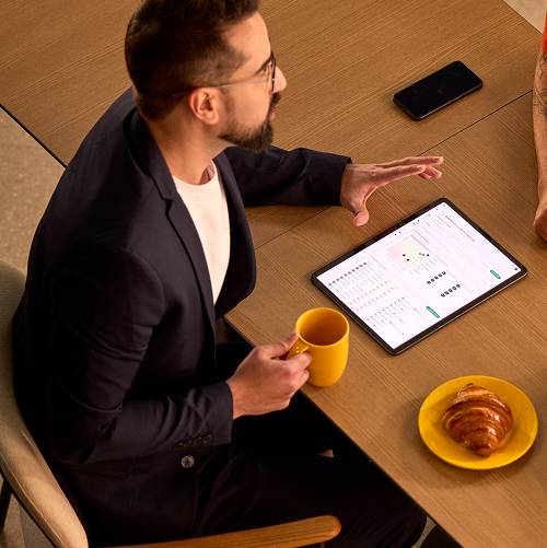pessoa sentada na mesa tomando café enquanto discute uma planilha