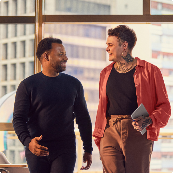 Two people talking in an office in front of a window overlooking the city a