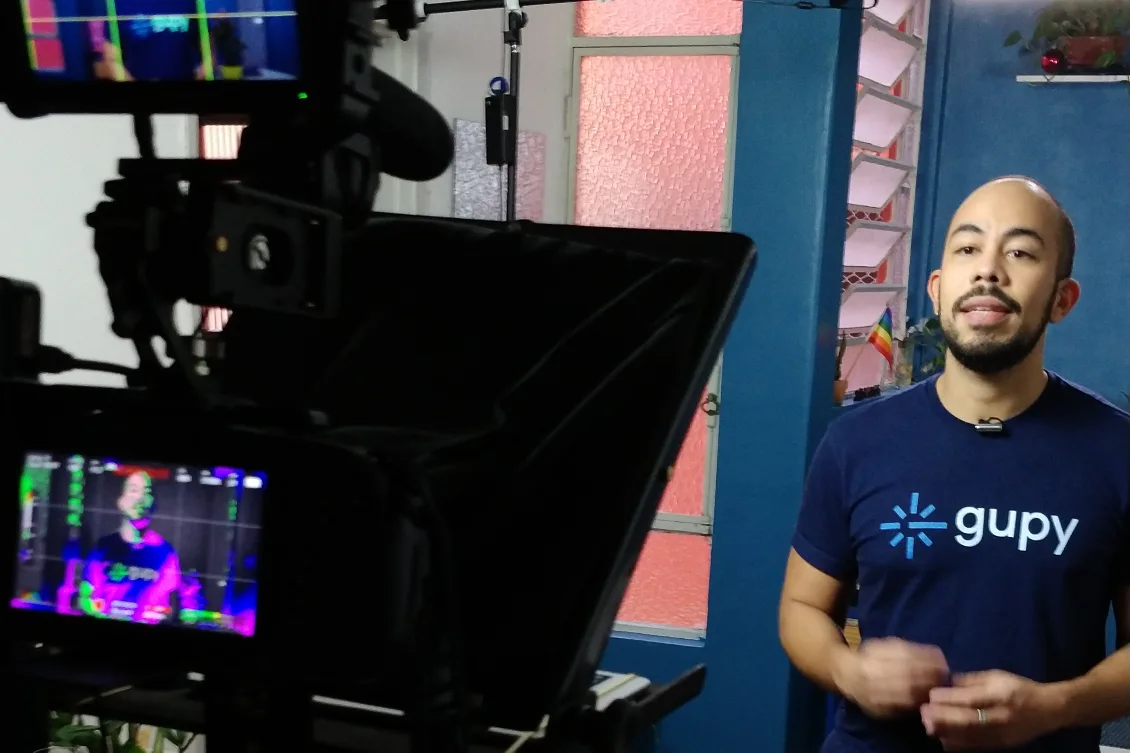 Pessoa utilizando uma camiseta da Gupy em frente a uma câmera